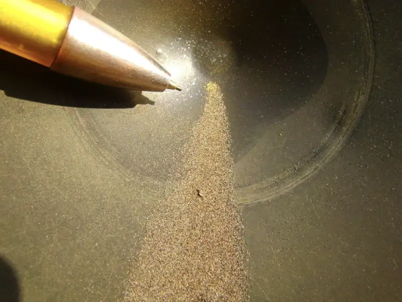 Concentrated heavy mineral sand with visible gold specks.